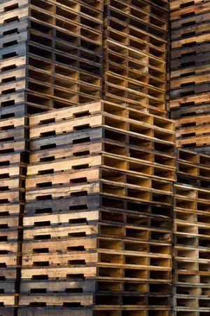 Tall stacks of recycled wood pallets close-up view